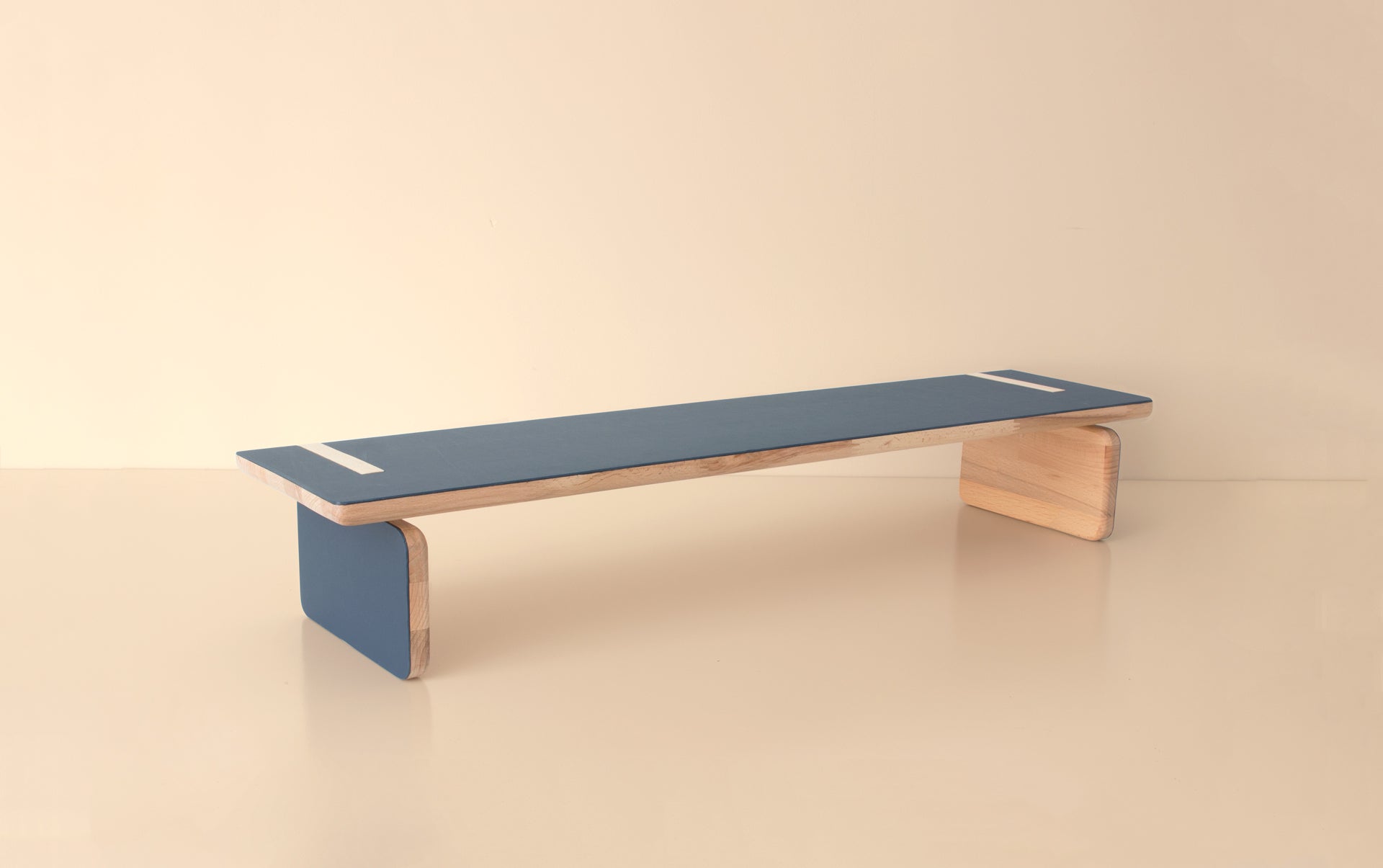 Side angle of minimalist wooden bench with deep blue finish and natural wood edges