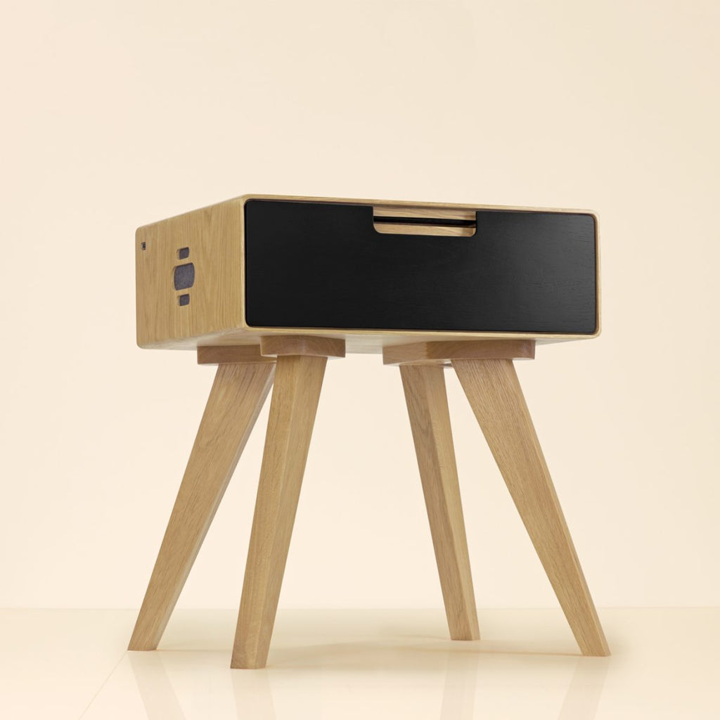 Elegant natural wood side table with black drawer and four angled legs against beige background