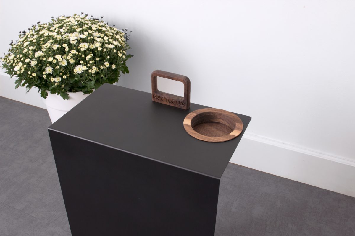 Close-up top view showing wooden handle and circular wooden bowl inset on black table surface